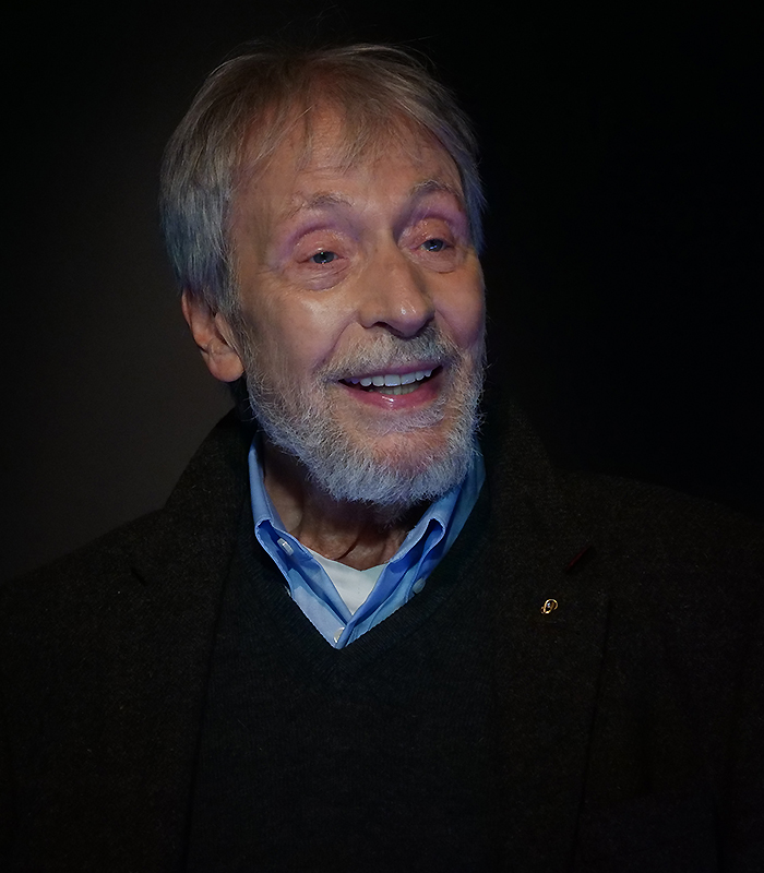 Wolfgang Keuter Wolfgang Keuter im schwarzen Bühnenraum. Er Trägt ein hellblaues Hemd und einen schwarzen Pille. Sein blick ist nach vorne rechts gerichtet. Er zeigt einen freundlichen und interessierten Gesichtsausdruck.