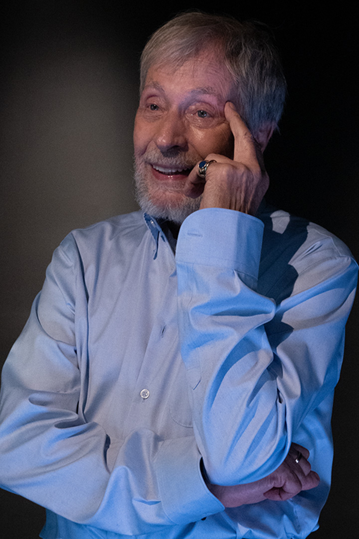 Wolfgang Keuter im hellblauen Hemd. Er sieht interssiert mit Mimik einem Teilnehmer beim Üben zu. Er ist als Porträt abgebildet.